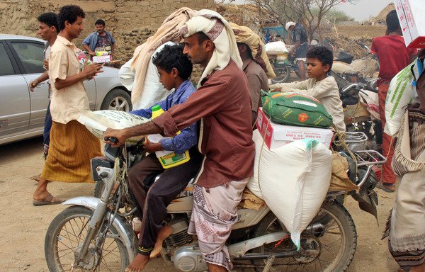 This picture taken on July 17th shows displaced Yemenis from al-Hodeidah receiving food aid from a Japanese NGO in the northern district of Abs, in Hajjah province. [Essa Ahmed/AFP]