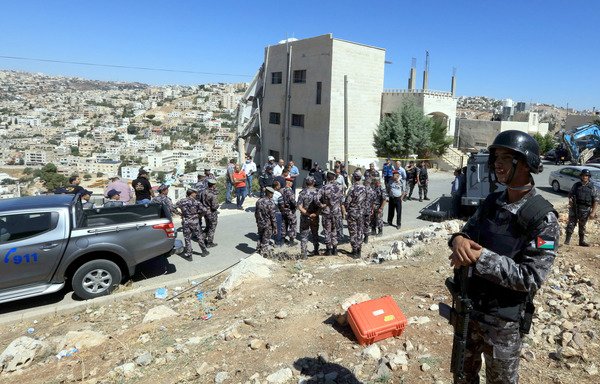 Jordanian forces gather near a damaged building in the city of Salt on Sunday (August 12th). Jordanian forces killed three extremists and arrested five others during a raid the previous day. [Khalil Mazraawi/AFP]