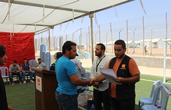 لاجئون سوريون من خريجي برنامج الرخصة الدولية لقيادة الحاسب الآلي يتسلمون شهاداتهم في مخيم الزعتري يوم 27 آب/أغسطس. [حقوق الصورة للمجلس النرويجي للاجئين]