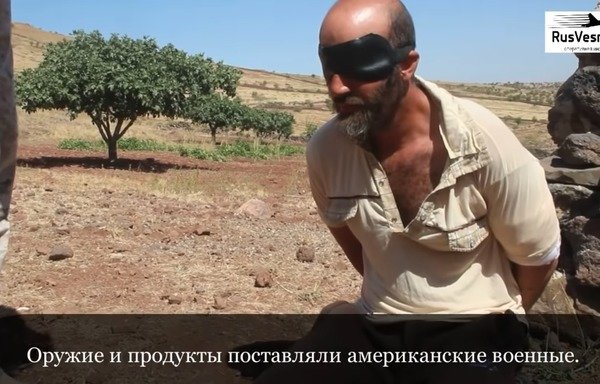 A screenshot from a video propagated by a Kremlin-backed website shows the interrogation of an alleged ISIS fighter. The subtitle says, "The Americans provided food and weapons." The subtitles not only misconstrue the answers but also hide the obvious coaching. [File]