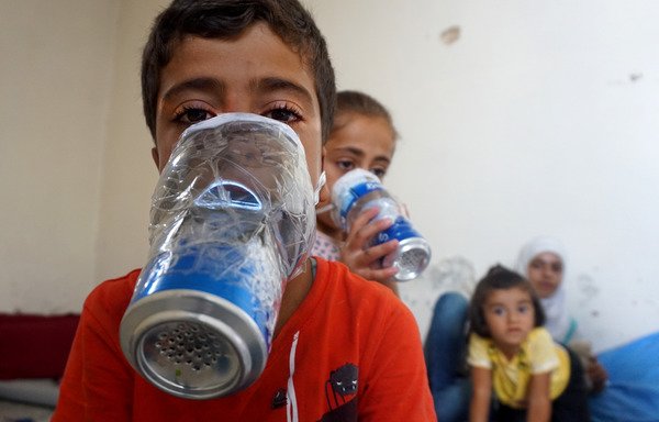 Children on September 12th try on improvised gas masks in Binnish in Syria's Idlib province. The Syrian regime and its Russian ally are threatening to retake Idlib. [Muhammad Haj Kadour/AFP]