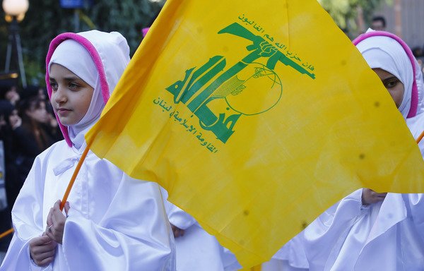 A Lebanese supporter carries a Hizbullah flag during Ashura in Beirut on September 20th. [Stringer/AFP]