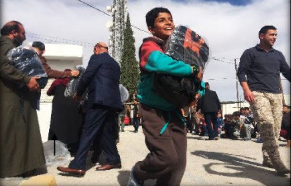 تلميذ في مدينة معان في جنوب الأردن يتلقى حقيبة تحتوي على اللوازم الدراسية في إطار حملة لتوزيع المساعدات في المحافظة الفقيرة. [ملف]