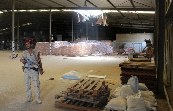 A soldier with the Arab coalition stands guard at a damaged warehouse of Yemen's Red Sea Mills company in the port city of al-Hodeidah on January 22nd. [Saleh al-Obeidi/AFP] 