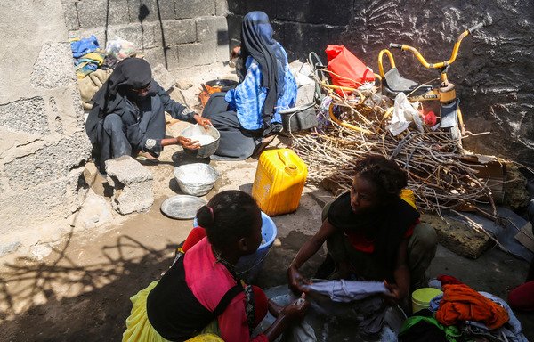 Yemeni women from a poor family prepare food for cooking as other girls wash clothes in a metal basin in a shack in the Red Sea port city of al-Hodeidah on January 11th. [AFP]