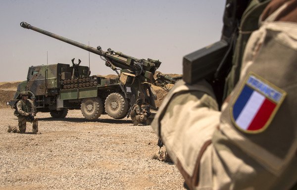 French soldiers from the Wagram Task Force kneel next to a unit of CAESAR, a French self-propelled 155 mm howitzer, north of Mosul in this file photo from July 13th, 2017, as the French army provides military support for Iraqi forces fighting ISIS. [Fadel Senna/AFP] 