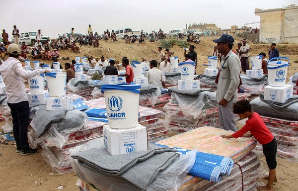 Displaced Yemenis receive humanitarian aid donated by the Norwegian Refugee Council and the UN High Commissioner for Refugees in Hajjah province on March 11th. [Essa Ahmed/AFP]