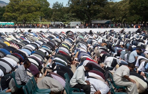 مسلمون يشاركون في صلاة الجمعة خلف إمام مسجد النور جمال فودة أثناء تجمع أقيم للصلاة والوقوف دقيقتين صمت حدادا على أرواح ضحايا المذبحة التي استهدفت مسجدين، وذلك في هاجلي بارك بمدينة كرايستتشرتش يوم 22 آذار/مارس. [مارتي ميلفيل/وكالة الصحافة الفرنسية]