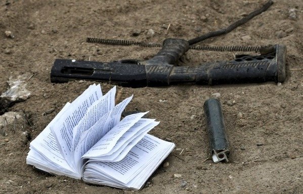 This picture taken on March 24th shows a discarded book written in Arabic and Russian, next to a broken gun, lying on the ground in the village of al-Baghouz, a day after ISIS was declared defeated by the SDF. [Giuseppe Cacace/AFP]