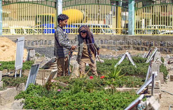 Yemeni children water plants and clean tombstones in a Sanaa cemetery on March 25th. [Mohammed Huwais/AFP]