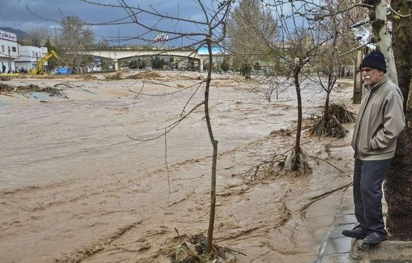 An Iranian man watches floodwaters sweep through his area during the recent flooding. [Photo circulated on social media]