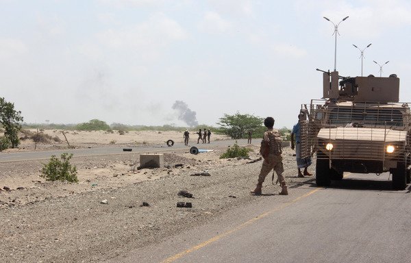Forces loyal to the Yemeni government stand guard as smoke billows on a road on the entrance to Abyan province during an operation to drive al-Qaeda out of the provincial capital on April 23rd, 2016. [Saleh al-Obeidi/AFP]