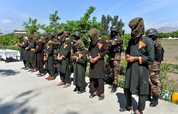 In this photo taken on April 10th, 2019, members of the Afghan security forces stand behind alleged ISIS fighters being presented to the media in Jalalabad, following their arrest. Afghan officials said five ISIS fighters and three Taliban militants were arrested with magnetic bombs and other ammunition during an operation in Nangarhar province. [Noorullah Shirzada/AFP]