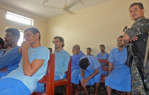 Members of the crew of an Iranian vessel loaded with rockets and explosives that was seized in Yemeni territorial waters in January 2013 stand for trial at the criminal court in Aden on April 23rd of that year. [Gamal Noman/AFP] 