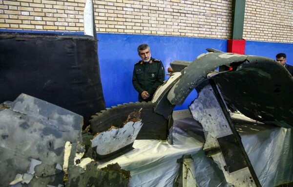 Gen. Amir Ali Hajizadeh, Iran's Head of the IRGC's aerospace division, looks at debris from a downed US drone reportedly recovered within Iran's territorial waters and put on display in the capital Tehran on June 21st, 2019. The Pentagon says the drone was above international waters when it was hit. [Meghdad Madadi/TASNIM NEWS/AFP]