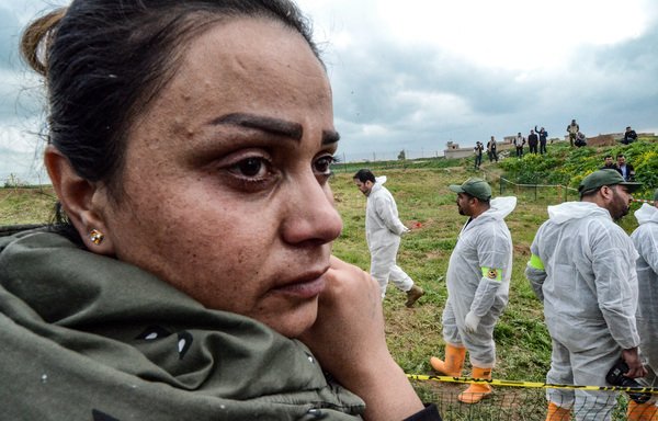 An Iraqi Yazidi woman watches on March 15th as forensic workers inspect a zone during the exhumation of a mass grave of hundreds of Yazidis killed by ISIS in Kojo village, Sinjar District. [Zaid al-Obeidi/AFP]