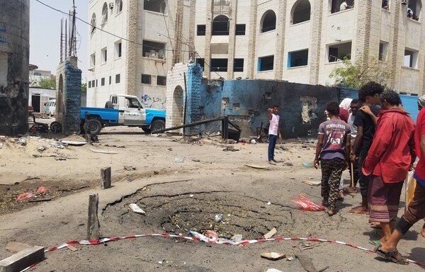 Yemenis walk past a crater at the site of a suicide car bombing on a police station in Aden's al-Sheikh Othman district on Thursday (August 1st). [Nabil Hasan/AFP]