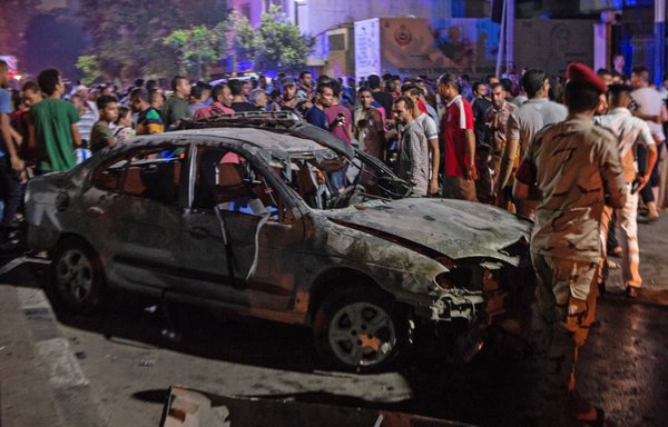 Onlookers and Egyptian security forces gather around a charred car, following an accident just before midnight on August 4th, outside the National Cancer Institute in central Cairo. [Aly Fahim/AFP]