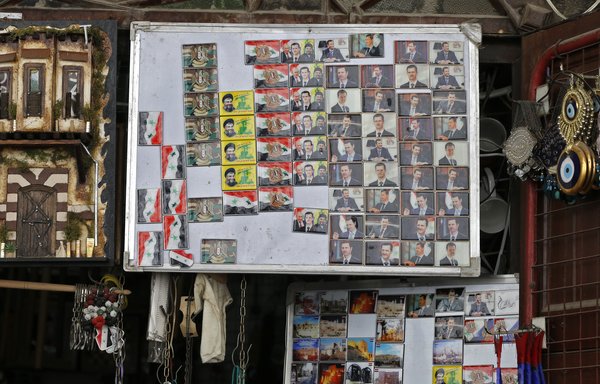 Magnets bearing the portraits of Syrian President Bashar al-Assad, Russian President Vladimir Putin and Hizbullah leader Hassan Nasrallah, are offered for sale in the old city of Damascus on March 12th. [Louai Beshara/AFP]