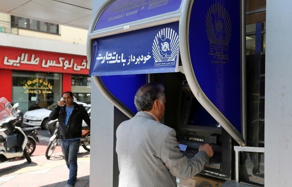 إيرانيون يسحبون المال من صراف آلي أمام مصرف في طهران في 24 نيسان/أبريل. [عطا كيناري/وكالة الصحافة الفرنسية]