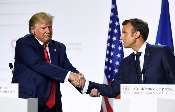 In this file photo taken on August 26th, French President Emmanuel Macron (R) and US President Donald Trump shake hands as they deliver a joint press conference in Biarritz, south-west France on the third day of the annual G7 Summit. [Bertrand Guay/AFP]