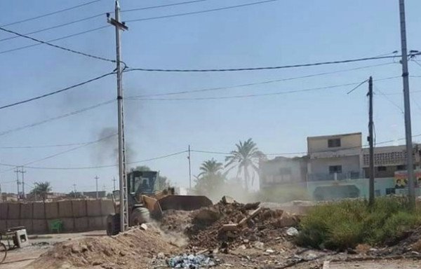 یک دستگاه بلدوزر سپاه پاسدارن انقلاب اسلامی به ایجاد خاک ریز مشغول ودیوارهای هسکو بلاست درپشت آن دیده می شود به همراه عکسهای بزرگ خمینی و خامنه ای رهبرپیشین و کنونی ایران که بردرورودی مقر سپاه در حومه دیرالزور آویخته شده است. [عکس به گردش درآمده در رسانه های اجتماعی]