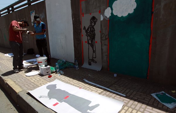 Yemeni artists work on a mural as part of a campaign to end the recruitment of child soldiers by tribal militias on April 10th, 2014 in Sanaa. [Mohammed Huwais/AFP]