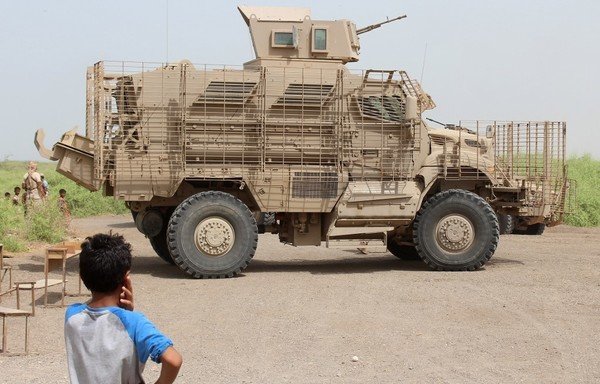 A Yemeni child looks at an armoured vehicle as members of the Emirati armed forces take part in a campaign to raise awareness against mines and IEDs, south of Mokha, western Yemen, on July 22nd, 2018. [Saleh al-Obeidi/AFP]