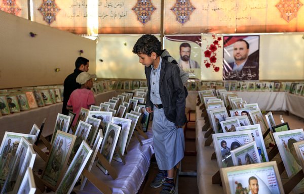 A Yemeni boy looks at portraits of Houthi fighters who were reportedly killed in action during an exhibition marking 'Martyrs' Day' in Sanaa on January 22nd. [Mohammed Huwais/AFP]