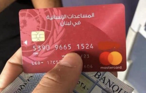 A Syrian refugee in Lebanon uses his UN-issued red card to withdraw winter aid money. [Nohad Topalian/Al-Mashareq]