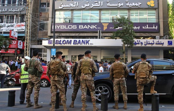 Members of the Lebanese army surround protestors gathering outside a bank during continuing anti-corruption demonstrations on November 4th in Sidon. [Mahmoud Zayyat/AFP]