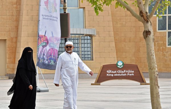 An elderly couple walks on November 12th past the main gate of King Abdullah Park in Riyadh, where a Yemeni expatriate stabbed four performers during a live play the previous day. [Fayez Nureldine/AFP]