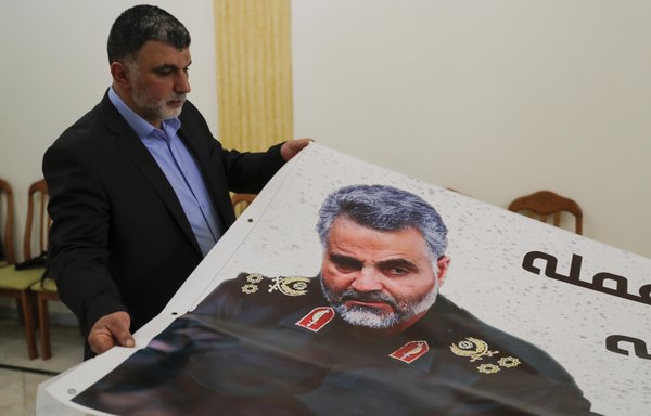 A worker at the Iranian embassy in the Lebanese capital Beirut adjusts a poster of IRGC Quds Force commander Qassem Soleimani, who was killed in a US strike on his convoy in Baghdad on January 3rd. [Anwar Amro/AFP]