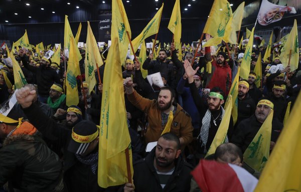 Hizbullah supporters wave flags as Hassan Nasrallah delivers a speech on a screen in Beirut's southern suburbs on January 5th. [Anwar Amro/AFP] 