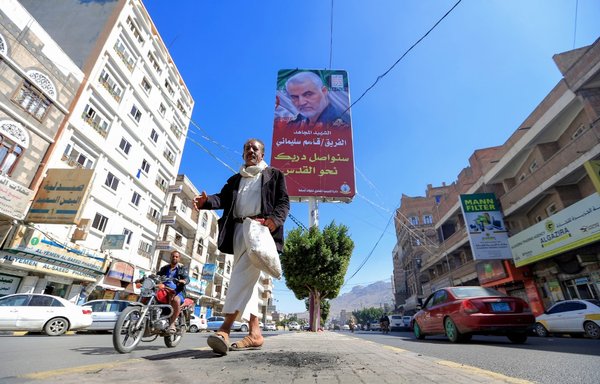 A Yemeni man walks beneath a poster of slain Iranian military commander Qasem Soleimani in Sanaa on January 8th. [Mohammed Huwais/AFP]