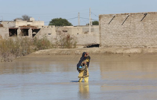 An Iranian woman walks through a flooded road on January 13th in the village of Dashtiari in Iran's Sistan-Baluchistan region, as severe downpour led to floods across the region, blocking roads and damaging homes. [Alireza Masoumi/ISNA/AFP]