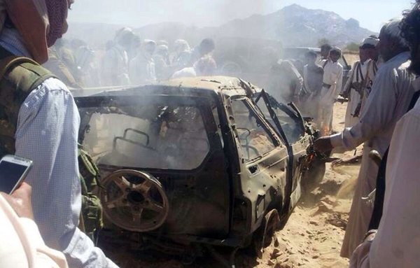 Yemenis gather around a burnt car after it was targeted by a drone strike killing three suspected al-Qaeda militants on January 26th, 2015 between the Marib and Shabwa provinces, a desert area east of Sanaa. [Stringer/AFP]