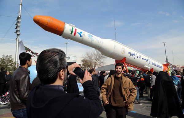 Iranians take pictures of the Simorgh (Phoenix) satellite rocket during events in Tehran to mark the 37th anniversary of the Islamic revolution on February 11th, 2016. [Atta Kenare/AFP]