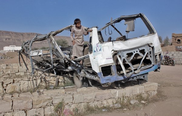 A Yemeni child stands in the wreckage of a bus that was hit by an airstrike on the Dahyan market in August 2018 while carrying school children in the province of Saada. [Stringer/AFP]