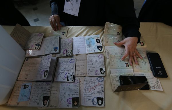 A poll worker checks identifications before Iranian voters can cast their ballot in a parliamentary election at a polling station in Tehran on February 21st. [Atta Kenare/AFP]