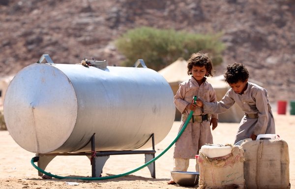Displaced Yemeni children, who fled the northern al-Jawf province due to fighting between the Houthis and Yemeni forces, fill water containers at a camp in the desert which lies some 80 kilometres from Marib province, on October 21st, 2015. [Abdullah al-Qadry/AFP]