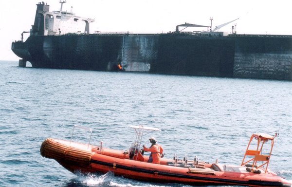 In this file photo from October 2002, Yemeni coastguards patrol in front of stricken French supertanker Limburg, still ablaze and leaking crude, as it is towed out into the Arabian Sea. The vessel was attacked by a small boat loaded with explosives off the south-eastern Yemeni port of al-Mukalla. [Khaled Fazaa/AFP]