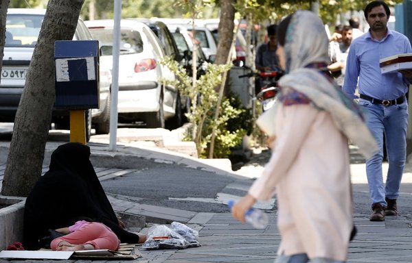 امرأة تتخطى متسولا في العاصمة الإيرانية طهران، يوم 31 تموز/يوليو 2018. [عطا كيناري/وكالة الصحافة الفرنسية]