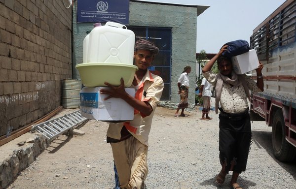 Displaced Yemenis receive aid at a school in al-Hodeidah city after being evacuated from a village in the province amid battles between Yemeni forces and the Houthis on June 17th, 2018. [Abdo Hyder/AFP]