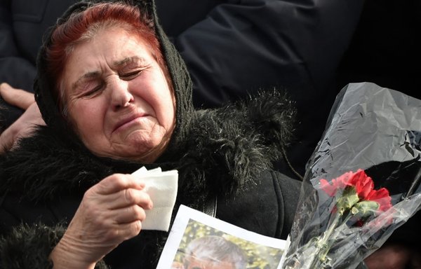 Relatives of the 11 Ukrainians who died in a plane mistakenly shot down by Iran in January, react during a ceremony unveiling a memorial stone at the site of the future monument at the Boryspil International airport outside Kiev on February 17th. [Sergei Supinsky/AFP]