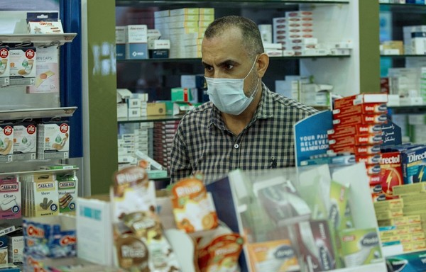 A pharmacist works at a drugstore while wearing a face mask in Iraq's southern city of Basra on March 18th, 2020. Seeking to stem an outbreak of the COVID-19 pandemic, more than half of Iraq's 18 provinces have declared curfews of several days. [Hussein Faleh/AFP]