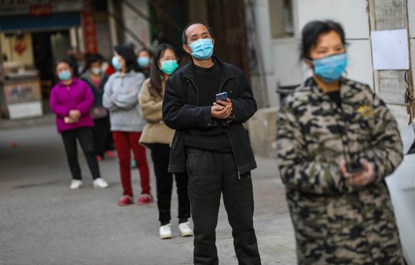 Residents line up to pick up pork which was delivered to their quarantined compound in Wuhan, in China's central Hubei Province on March 18th. Undeniable scientific and anecdotal evidence proves the COVID-19 coronavirus originated from Wuhan, despite official Chinese attempts to change the narrative. [STR/AFP]