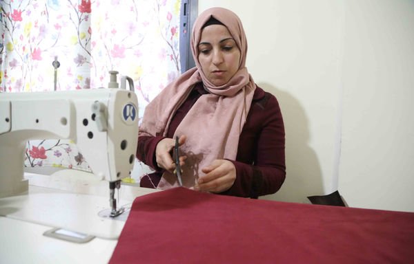 باستخدام ماكينتي خياطة في منزلها، تستطيع حُسن محمد طعمة دعم عائلتها وتوفير بعض أرباحها لتنفيذ استثمارات مستقبلية. [حقوق الصورة لجمعية خادمي الغد]