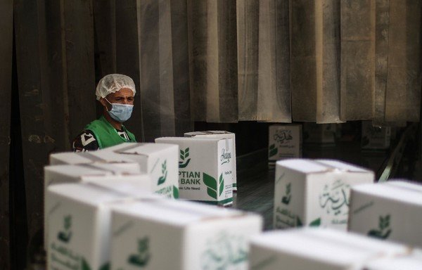 A worker of NGO Egyptian Food Bank prepares cartons with foodstuffs to distribute to people who lost their jobs due to the coronavirus pandemic crisis, in the Egyptian capital Cairo, on April 5th. [Mohammed al-Shahed/AFP]