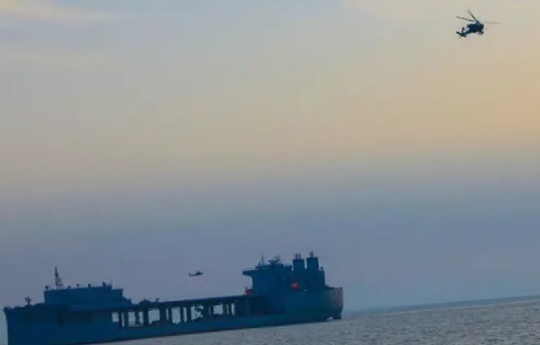 An Apache helicopter flies over a naval vessel during US exercises conducted in the Gulf region in March. [US Army]
